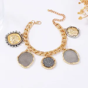 Detail view of a gold-plated link chain bracelet with various metal coin charms