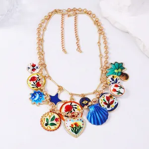 Détail d'un collier double chaîne dorée avec breloques en émail coloré au style bohème