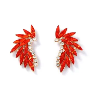 Close-up of gold-plated feather ear cuffs featuring red marquise and white round crystals