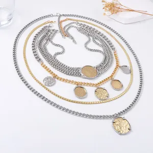 Multi-layer gold and silver tone chain necklace with textured metal coin pendant