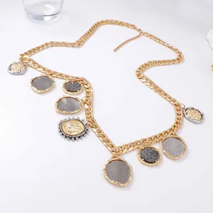 Detailed close-up of gold chain belt with embossed geometric coin pendants and lava texture