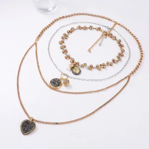 Close-up of layered chain necklaces with heart and vintage coin pendants for women