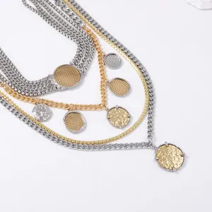 Macro detail of layered gold and silver chains with textured coin charms on a white surface