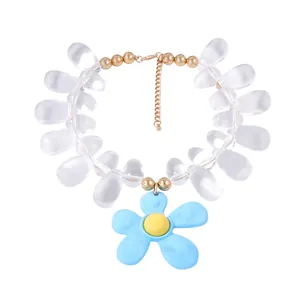 Detail of beaded necklace with clear teardrop beads and a blue flower pendant