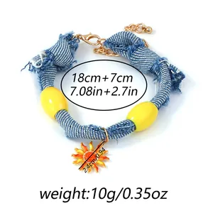 Detail of blue denim cord bracelet with sun pendant and yellow beads showing lobster clasp