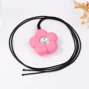 Gros plan d'un collier pendentif fleur rose en 3D avec cristal et cordon noir