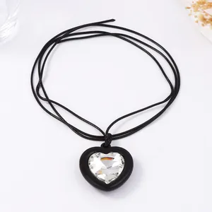 Gros plan détaillé d'un pendentif cœur avec cristal sur un collier en cordon noir tressé
