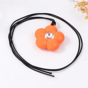 Détail d'un collier pendentif fleur orange en résine avec un cristal étincelant