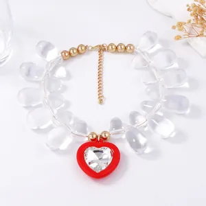 Detail of clear teardrop beads and red heart pendant with crystal on gold chain necklace