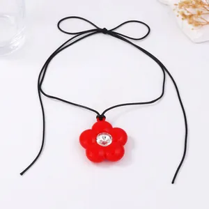 Détail du collier fleur rouge avec cristal central et cordon noir à nouer