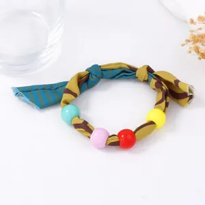 Macro detail of multi-color fabric woven bracelet with vibrant large acrylic beads