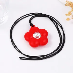 Détail d'un pendentif fleur rouge avec strass central sur un collier cordon noir