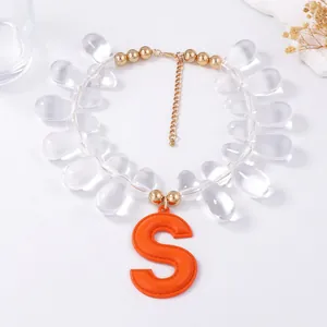 Detailed view of beaded necklace with teardrop beads and large orange S letter pendant