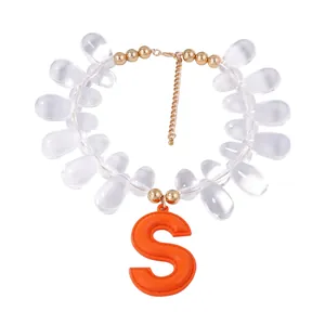 Detail of beaded necklace with orange leather S pendant and golden metal accents