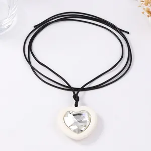 Collier avec pendentif cœur minimaliste serti de zircone sur cordon noir sur fond blanc