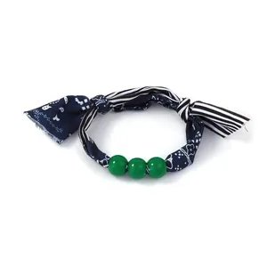 Detail of paisley fabric bracelet with green beads and striped textile texture