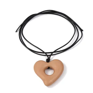 Détail d'un pendentif cœur en pierre rose minimaliste sur un collier en cordon noir