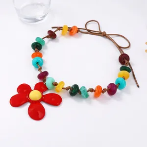 Dettaglio collana con perline colorate e grande ciondolo a forma di fiore rosso