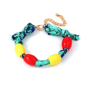 Detail of floral fabric wrap bracelet with red yellow beads and gold lobster clasp