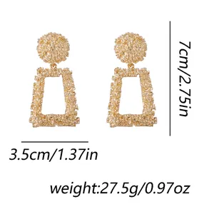 Gros plan sur boucles d'oreilles dorées géométriques mesurant 7x3,5cm avec relief texturé