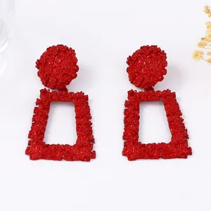 Vue détaillée des boucles d'oreilles géométriques rouges avec motif en relief texturé