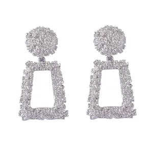 Gros plan de boucles d'oreilles géométriques en argent avec textures florales en relief