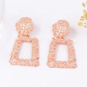 Détails de boucles d'oreilles trapèze or rose avec texture métallique effet lave