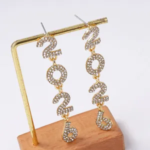 Detailed macro view of long gold alloy 2026 drop earrings encrusted with sparkling white rhinestones
