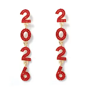 Close-up of dangling gold-plated earrings featuring 2026 numbers with red rhinestones