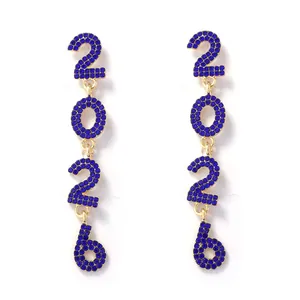 Close-up of gold 2026 dangle earrings with pavé-set blue crystals for New Year