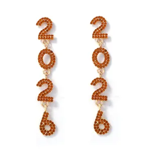 Macro view of gold dangling earrings with orange rhinestones forming 2026 numbers