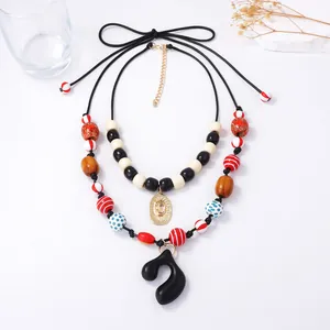 Detail of double-layered beaded necklace with black resin pendant and golden charms