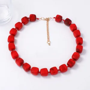 Minimalist necklace with large red geometric resin square beads and gold clasp on white background