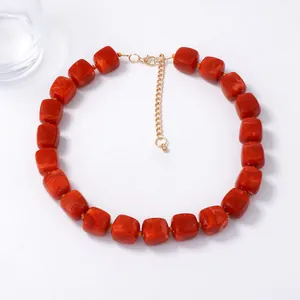 Macro detail of reddish-brown resin cubic beads and gold adjustable chain on a necklace