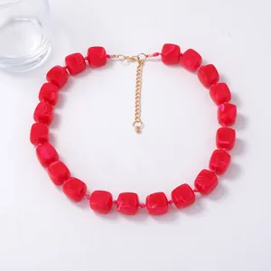 Detail of red square resin beads with marble texture and golden adjustable chain