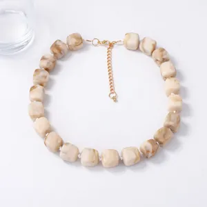 Detail view of geometric resin cube necklace with marble pattern and golden clasp