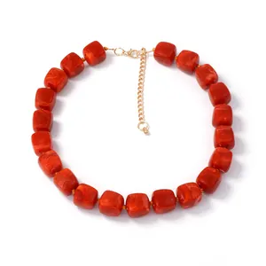 Macro detail of red resin cube beads with marble texture and gold adjustable clasp