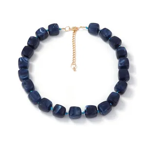 Macro detail of deep blue marble resin cube beads with gold adjustable chain necklace