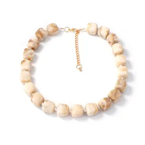 Detail of marble textured resin beads on a necklace with golden adjustable extender chain