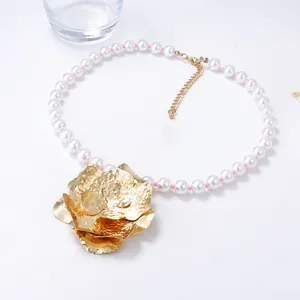 Vue macro de perles blanches avec perles roses et pendentif fleur dorée texturée