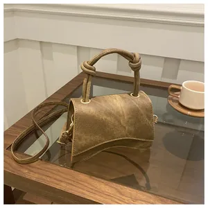 Detail of vintage brown textured crossbody bag with curved base and knotted handle
