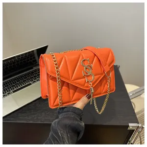 Detail einer orangefarbenen Stepptasche mit goldener Kette und S-Metallquasten-Logo