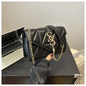 Detail der schwarzen Stepptasche mit großem goldenem S-Logo und Quasten-Dekoration