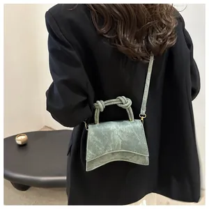 Detail of dark green vintage textured mini square bag with a knotted rope top handle