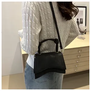Chic black crossbody bag with asymmetrical wave bottom and knotted top handle detail