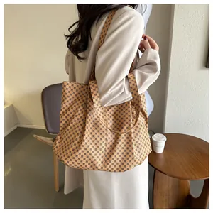 Grand sac cabas avec motif géométrique marron porté à l'épaule pour un look urbain