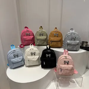 Mini backpack set in 8 colors featuring metallic bow detail on white display stands