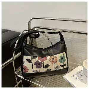 Detail van het bloemen jacquard patchwork en ritssluiting op de zwarte PU schoudertas