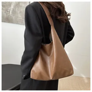 Rear view of a model wearing a brown vintage PU leather tote bag with a black blazer