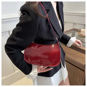 Detalle del bolso de media luna en charol rojo brillante con herrajes de metal dorado